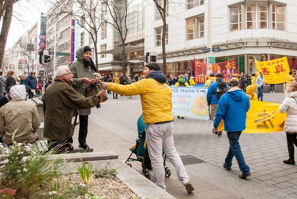 Gledatelji prihvaćaju letke s informacijama o Falun Dafa i o tekućem progonu u Kini.