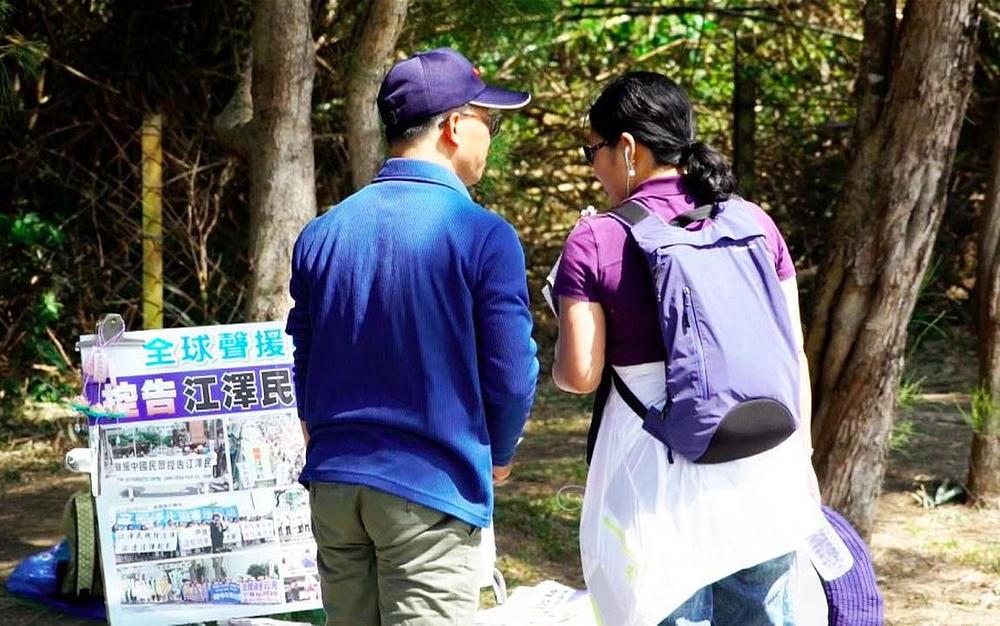 Gosp. Zheng Tonghe (lijevo) govori turistu o Falun Gongu i progonu. 