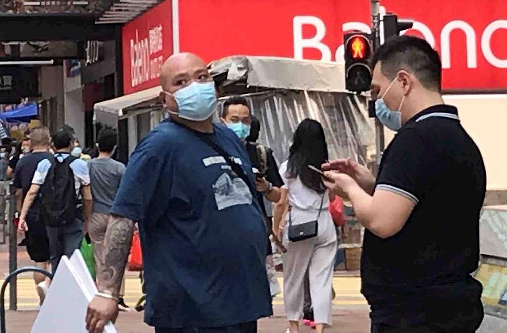 Dvojica su muškaraca i žena postavili transparente koji ocrnjuju Falun Gong pored uništenog Dafa štanda u ulici Argyle, Mong Kok, a jedan od njih je bio ćelavi čovjek s tetovažama na tijelu.