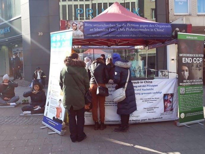 Prolaznik potpisuje peticiju na Falun Dafa štandu u Essenu 5. marta 2022. godine.